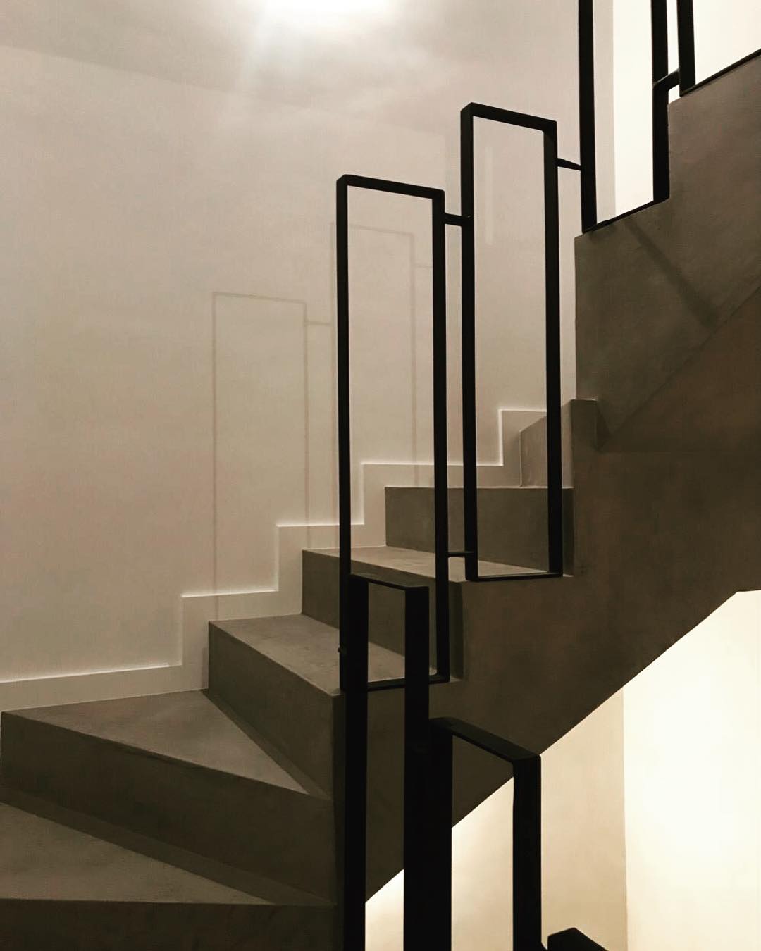 Escalera microcemento pulido · Barandilla acero negro · Acabado continuo sin juntas · Minimalista